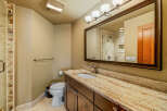 This stunning bathroom boasts a luxurious granite countertop and a stylish wooden vanity, offering both elegance and functionality.
