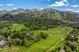 Experience luxury mountain living with this stunning aerial view of a golf course community nestled against a majestic mountain backdrop.