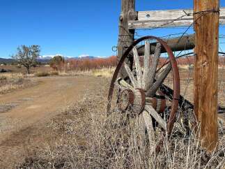 Discover the charm of this rustic property, featuring a weathered wagon wheel and a classic wooden fence.