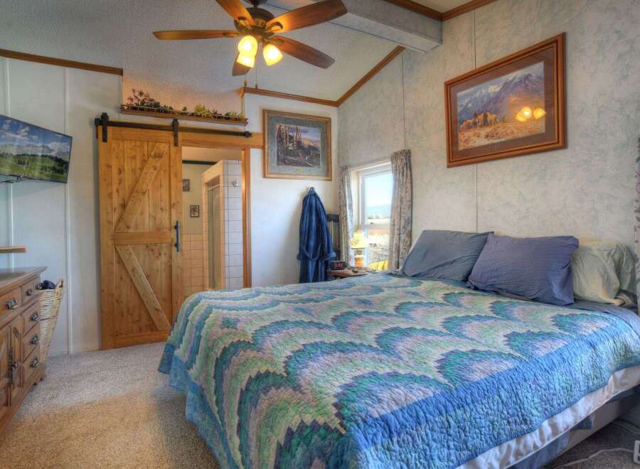 This charming bedroom features a rustic sliding barn door leading to a private bathroom.