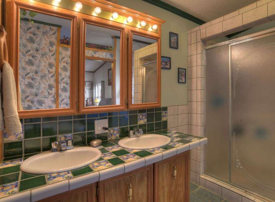 This charming bathroom features a double vanity with a unique tile countertop and matching backsplash, offering ample space and style.