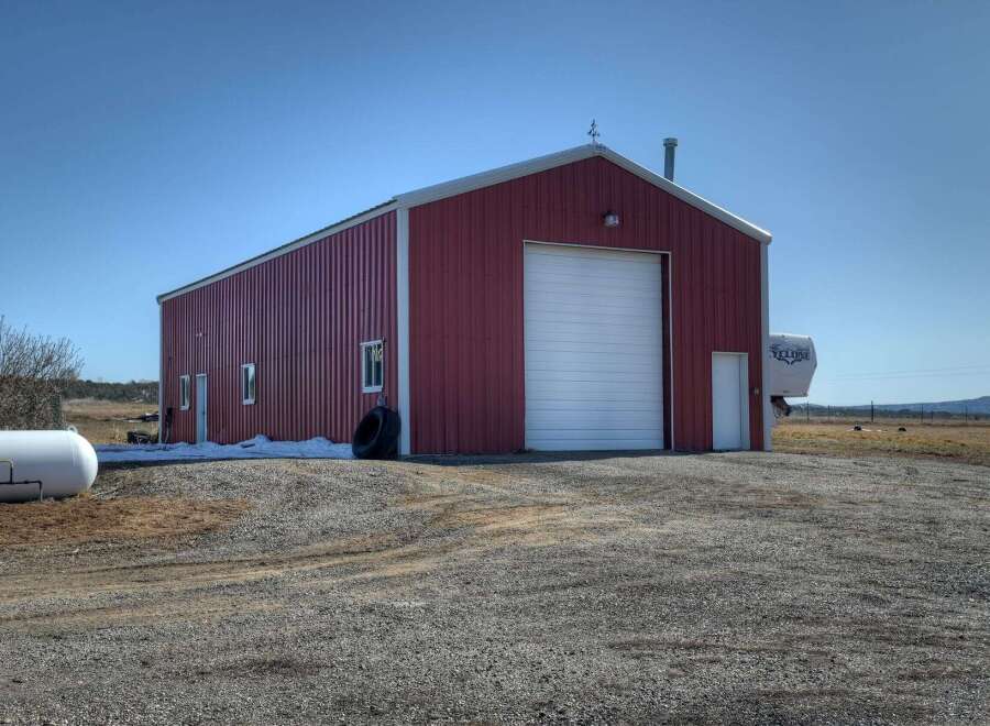 This property features a spacious red metal building, perfect for storage or a workshop.