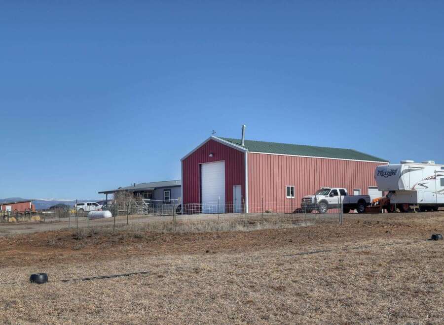 This property offers a spacious red barn with a green roof, perfect for storage or a workshop.