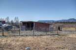 Discover the charm of this rural property, featuring a rustic red shed and expansive views of the surrounding landscape.