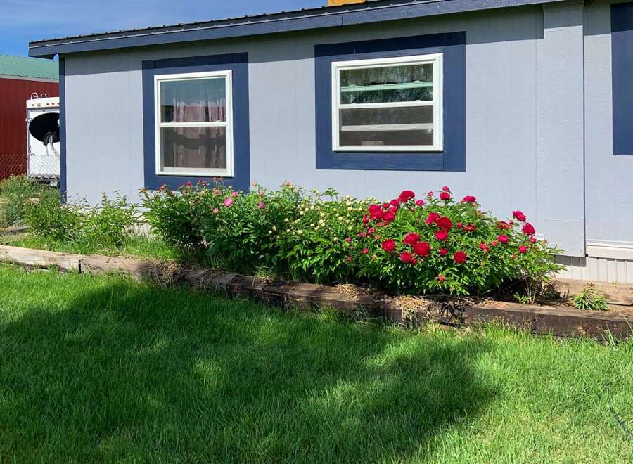 This charming property boasts a beautifully landscaped yard with vibrant red and white flowers, creating a welcoming curb appeal.