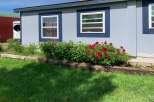 This charming property boasts a beautifully landscaped yard with vibrant red and white flowers, creating a welcoming curb appeal.