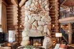 Experience rustic luxury in this stunning log cabin home, featuring a grand stone fireplace as the focal point of the living area.