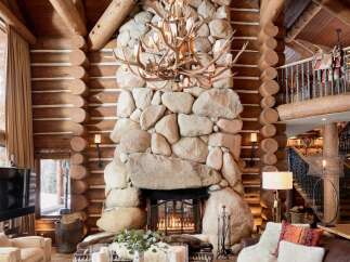 Experience rustic luxury in this stunning log cabin home, featuring a grand stone fireplace as the focal point of the living area.