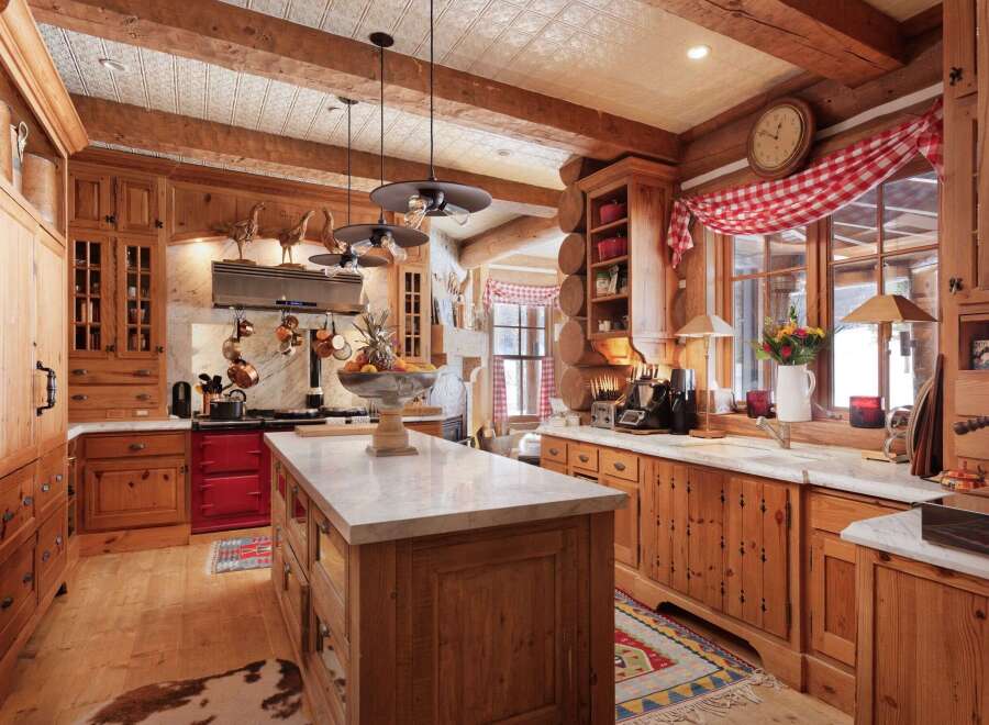 Step into rustic elegance with this stunning kitchen! Featuring custom wood cabinetry, a marble-topped island, and a vibrant red stove, this space is perfect for both cooking and entertaining.