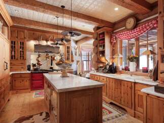 Step into rustic elegance with this stunning kitchen! Featuring custom wood cabinetry, a marble-topped island, and a vibrant red stove, this space is perfect for both cooking and entertaining.