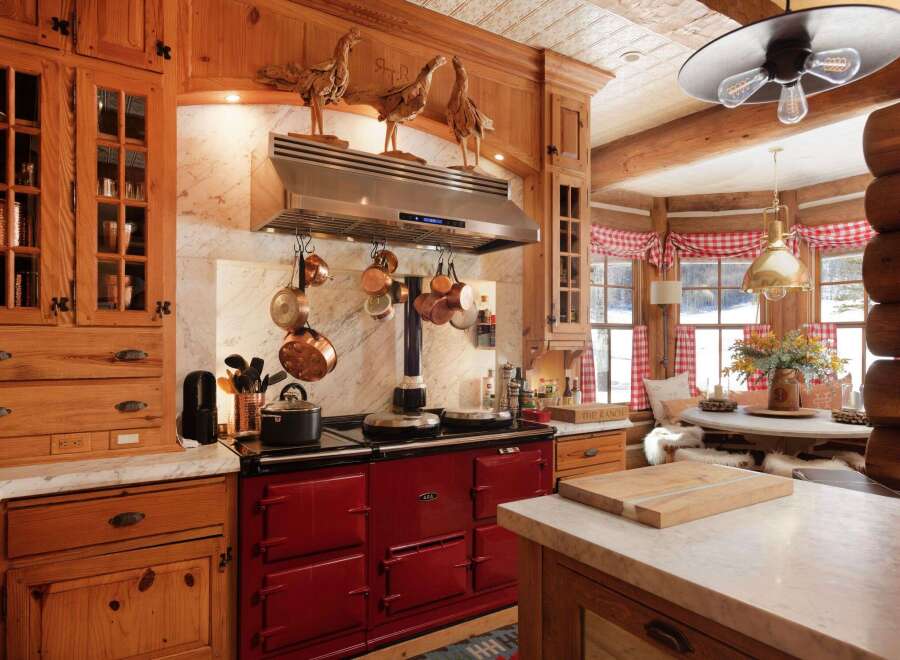 This stunning kitchen showcases a rustic charm with its wooden cabinetry and a striking red AGA stove.