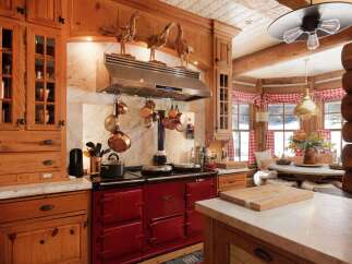 This stunning kitchen showcases a rustic charm with its wooden cabinetry and a striking red AGA stove.