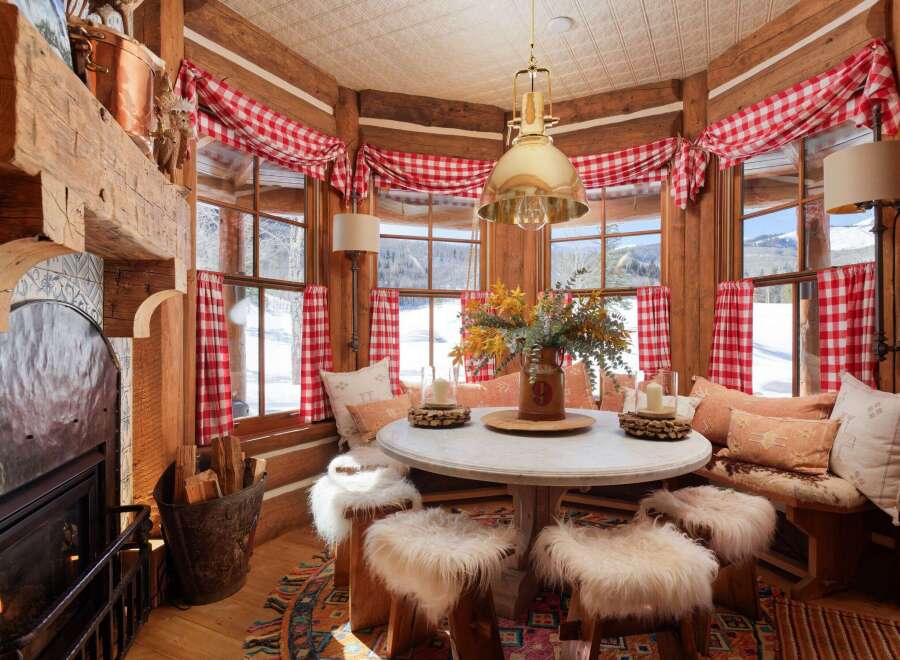This cozy cabin dining area features a round table surrounded by fur-covered stools, perfect for intimate gatherings.