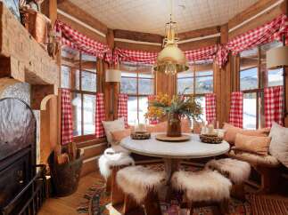 This cozy cabin dining area features a round table surrounded by fur-covered stools, perfect for intimate gatherings.