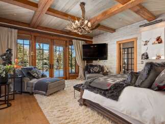 Experience luxury in this stunning bedroom featuring a rustic design with wooden beams and a cozy ambiance.
