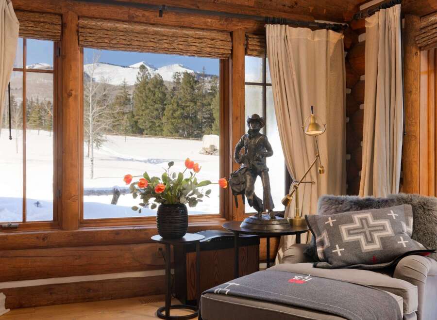 This cozy living space boasts stunning mountain views framed by rustic wooden windows.