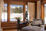 This cozy living space boasts stunning mountain views framed by rustic wooden windows.
