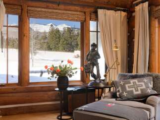 This cozy living space boasts stunning mountain views framed by rustic wooden windows.