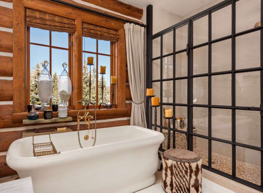 Indulge in the rustic charm of this luxurious bathroom, featuring a stunning clawfoot tub and a walk-in shower.