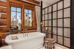 Indulge in the rustic charm of this luxurious bathroom, featuring a stunning clawfoot tub and a walk-in shower.