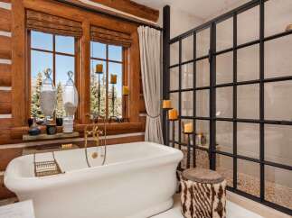 Indulge in the rustic charm of this luxurious bathroom, featuring a stunning clawfoot tub and a walk-in shower.