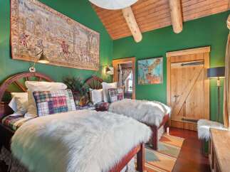 Step into rustic elegance with this charming bedroom, featuring twin beds adorned with plush faux fur throws and plaid accents.