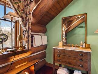 This rustic bathroom features a charming log cabin aesthetic, perfect for a cozy retreat.