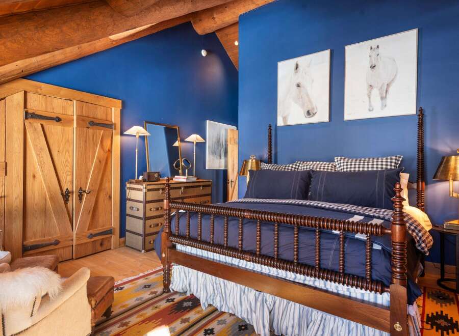 This stunning bedroom boasts a rustic charm with its wooden beams and rich blue walls.