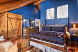 This stunning bedroom boasts a rustic charm with its wooden beams and rich blue walls.