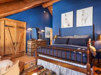 This stunning bedroom boasts a rustic charm with its wooden beams and rich blue walls.