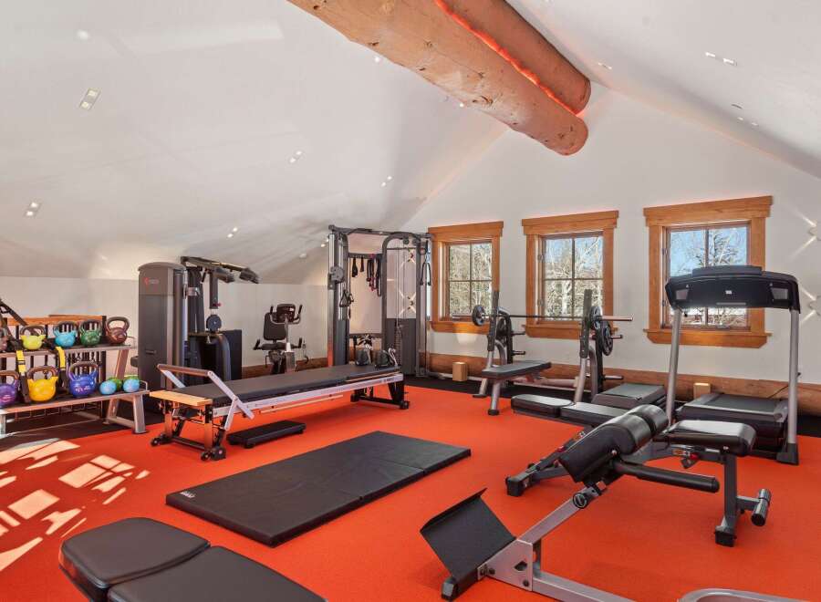 Step into your dream home gym! This space boasts a variety of workout equipment, including weight machines, free weights, and cardio machines, perfect for any fitness enthusiast.