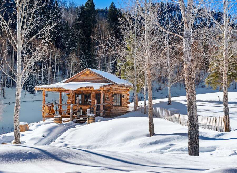 Nestled in a serene winter wonderland, this charming log cabin offers a cozy retreat.
