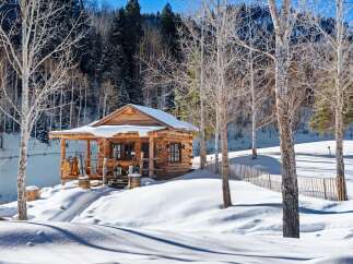 Nestled in a serene winter wonderland, this charming log cabin offers a cozy retreat.