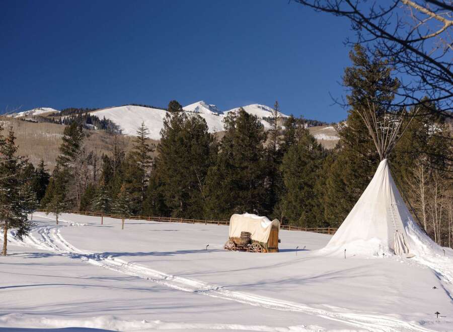 Experience the tranquility of this winter wonderland property, featuring a charming covered wagon and a traditional teepee.