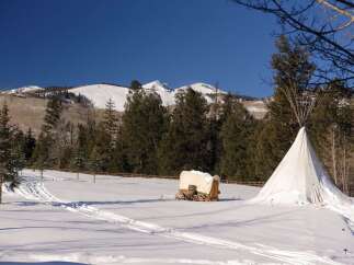 Experience the tranquility of this winter wonderland property, featuring a charming covered wagon and a traditional teepee.