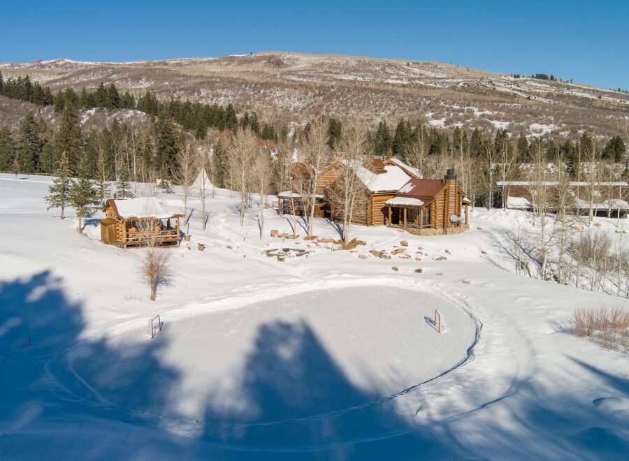 This stunning property boasts a luxurious log cabin nestled in a winter wonderland.
