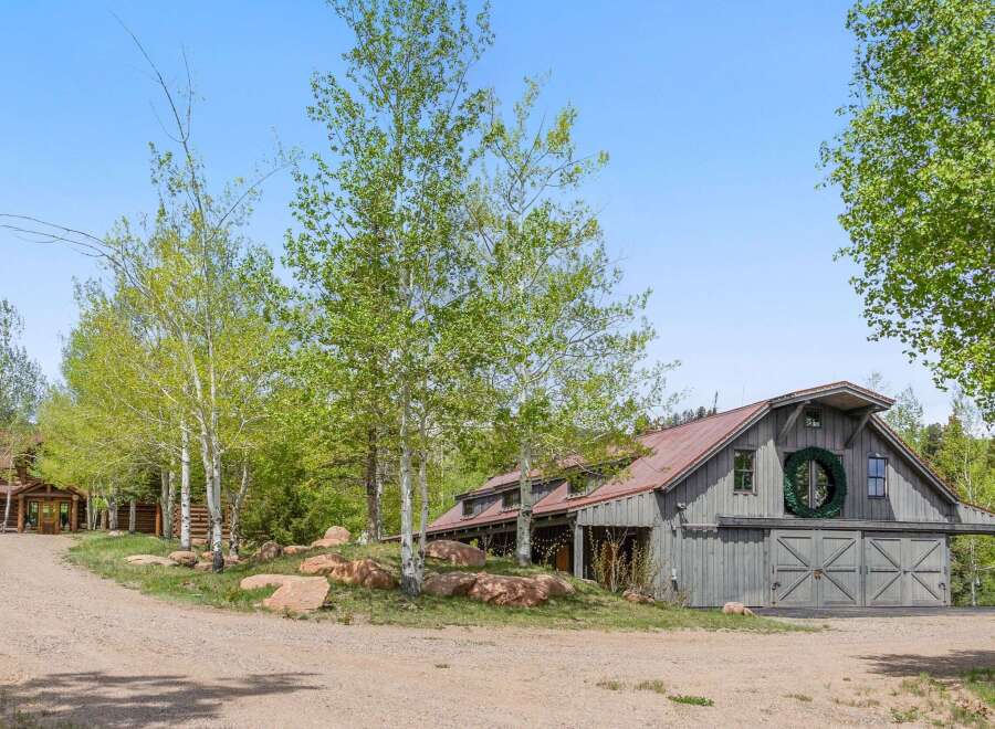 Nestled amidst lush greenery, this stunning property boasts a charming barn-style structure with a rustic aesthetic.