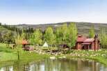 Experience serene mountain living with this picturesque log cabin nestled beside a tranquil pond.