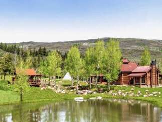 Experience serene mountain living with this picturesque log cabin nestled beside a tranquil pond.