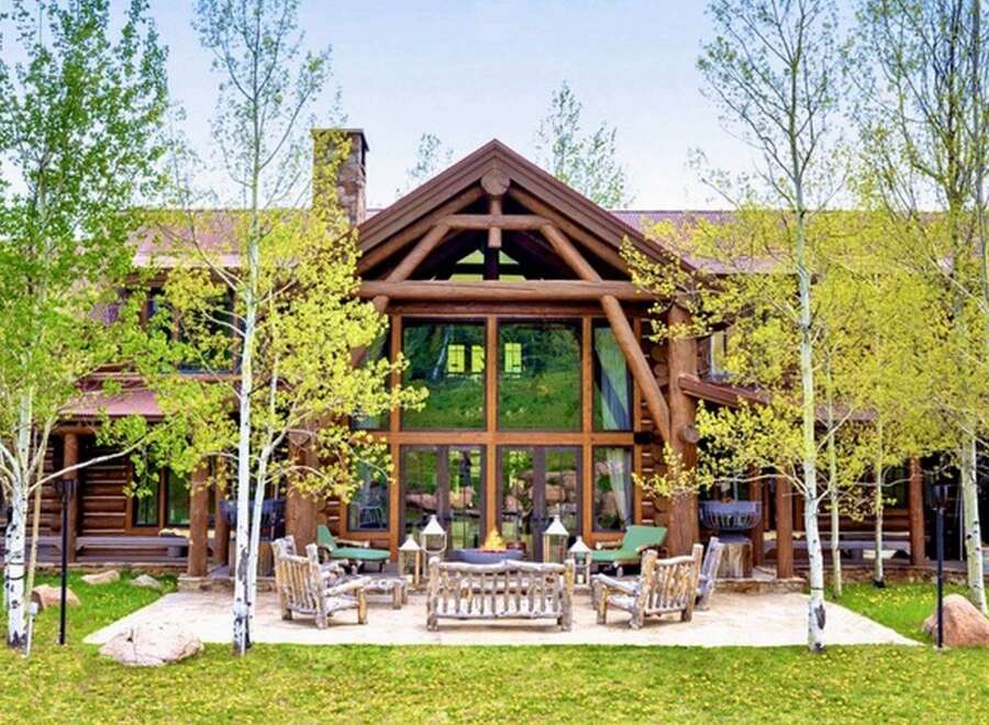 Experience rustic luxury in this stunning log cabin home, featuring a grand great room with floor-to-ceiling windows and exposed timber beams.