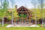 Experience rustic luxury in this stunning log cabin home, featuring a grand great room with floor-to-ceiling windows and exposed timber beams.