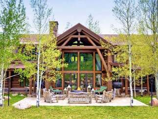 Experience rustic luxury in this stunning log cabin home, featuring a grand great room with floor-to-ceiling windows and exposed timber beams.
