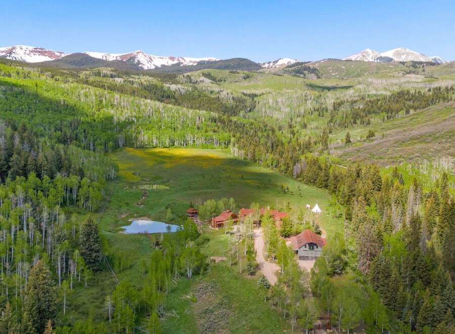 Escape to this stunning mountain retreat featuring multiple charming cabins nestled amidst lush aspen and pine forests.