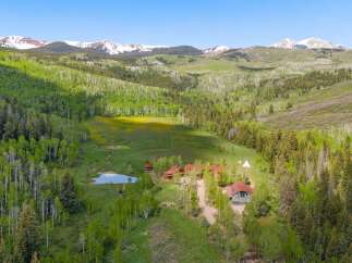 Escape to this stunning mountain retreat featuring multiple charming cabins nestled amidst lush aspen and pine forests.