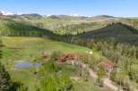 Discover this stunning mountain retreat featuring a sprawling log home with a rustic charm and a picturesque pond.