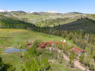 Discover this stunning mountain retreat featuring a sprawling log home with a rustic charm and a picturesque pond.