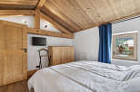 This charming bedroom features a cozy, rustic design with wooden beams and a sloped ceiling.
