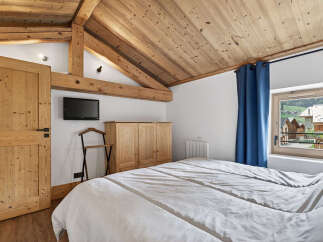 This charming bedroom features a cozy, rustic design with wooden beams and a sloped ceiling.