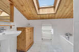 This charming bathroom features a unique wooden ceiling and a skylight, creating a bright and airy atmosphere.