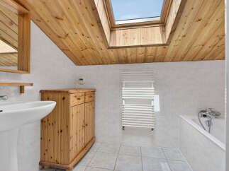 This charming bathroom features a unique wooden ceiling and a skylight, creating a bright and airy atmosphere.
